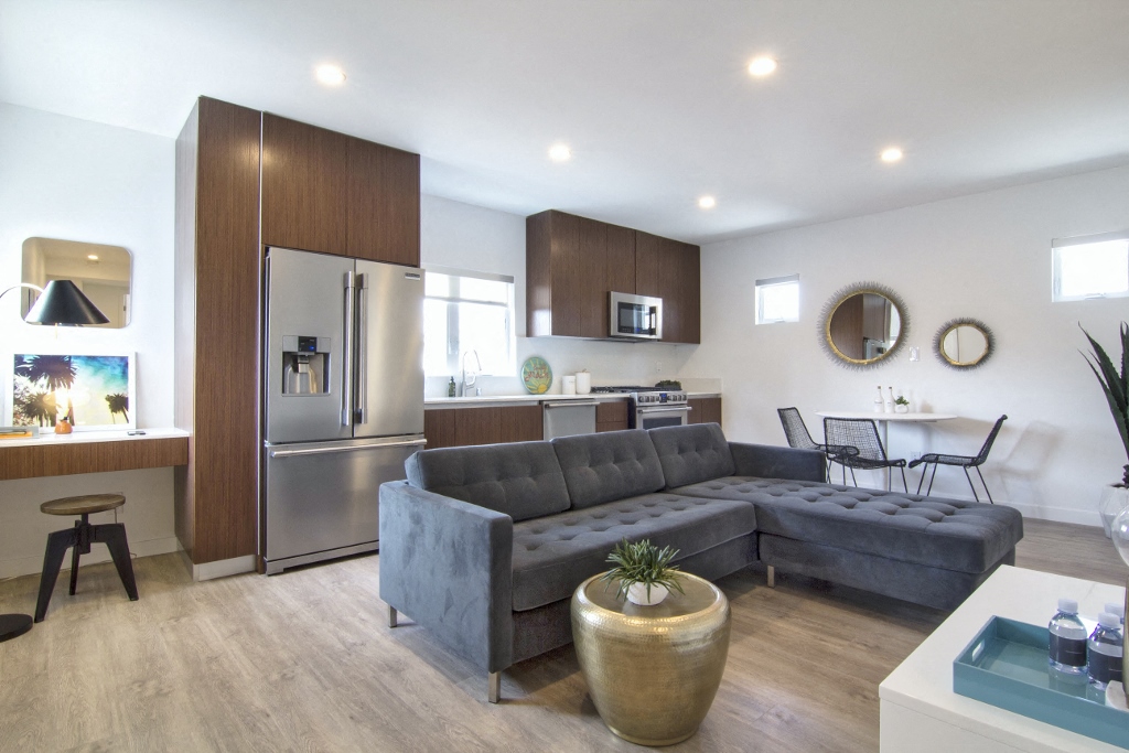 a living room with a gray couch and a kitchen in the background